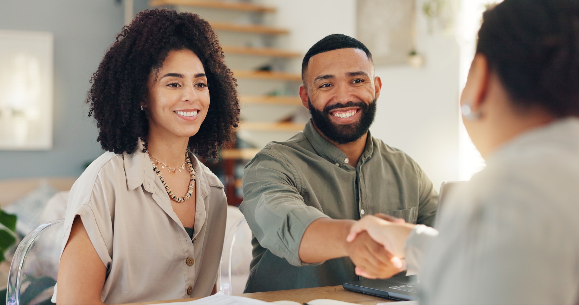 Handshake, meeting and couple with real estate agent for buying new home, house or property. Happy, deal and young man and woman shaking hands for apartment or building purchase with real estate agent.